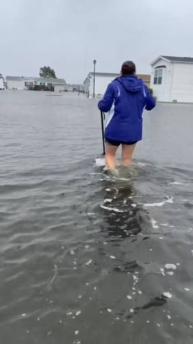 A person walking in the street has water up to their knees.