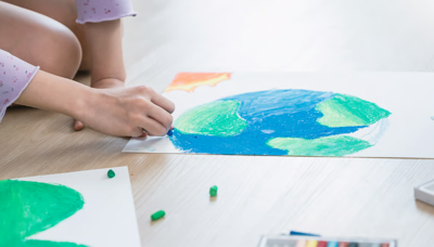 A KID COLORING A PICTURE OF THE EARTH.
