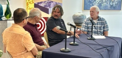 4 men sit at a table with mircrophones