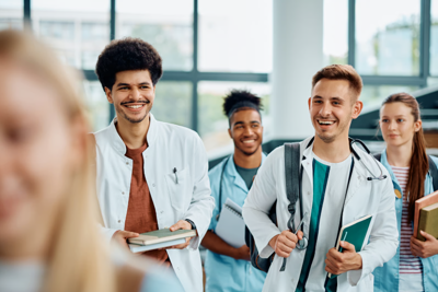 four students in white coats smiling