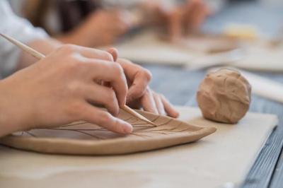 A hand stenciling on clay.