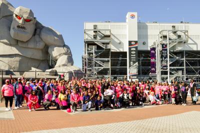 a large group of people are crowded around the entrance to the dover motor speedway while wearing pink clothing to support the delaware breast cancer coalition