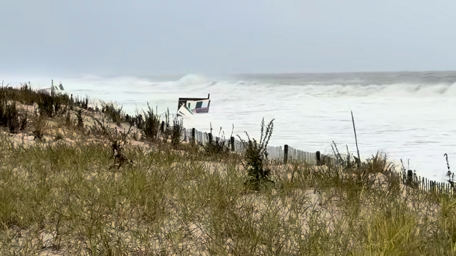 A structure gets taken down by waves as they approach the dunes.