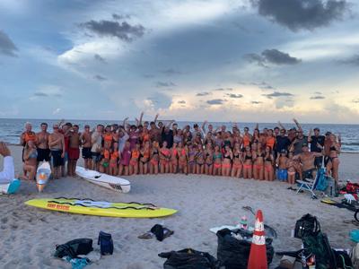 A large group of lifeguards posing on the beach.