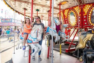 A mother and daughter smile while riding the carousel at the Delaware State Fair.