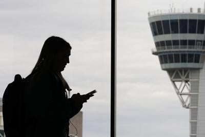The silhouette of a person on her phone with a traffic control tower in the background.