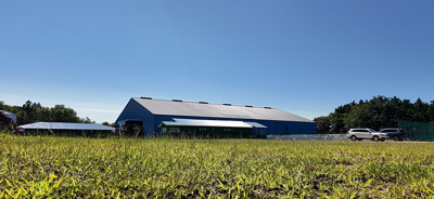 Blue metal building behind an empty grass field.