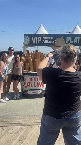 A woman takes a picture of three people beside a giant french fry prop.