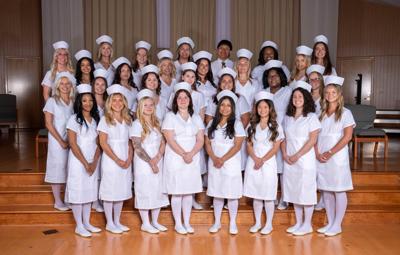 Students stand together in all white nurse uniforms.
