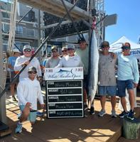 A group of men posing at the scales with an 80-pound white marlin, the tournament's largest catch.