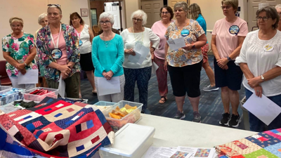 a group of people look around a table with quilts 