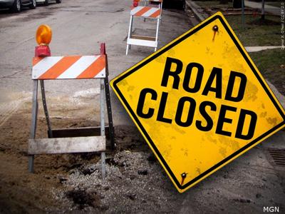 An image showing a road closed sign with traffic barriers placed a piece of on broken roadway.