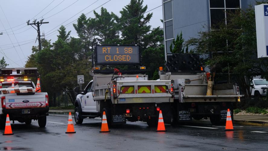 Orange traffic cones surround work trucks with a road sign lit up that says Route 1 southbound closed.