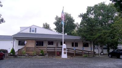 The front of Rehoboth Beach VFW Post 7447. A white monument is in front of flag pole flying the American and Delaware flags.