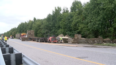 A tractor-trailer carrying chickens is on the side of the road with the containers mostly flipped.