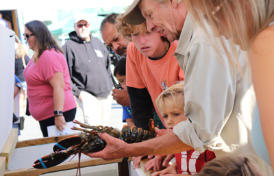 a man shows a child a live lobster up close