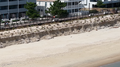 An aerial view of sand dropping off between the dune and the beach.