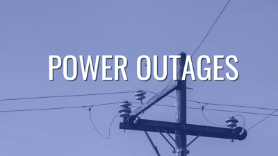 A powerline pole with the words "Power Outages" on top.