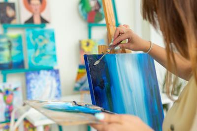 Woman artist working on painting in studio.