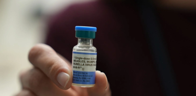 A close up of a person holding a measles vaccination vile.