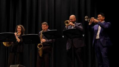 Four people lined up play instruments.