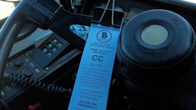 A physical bus pass on the steering wheel of a bus.