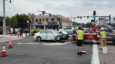 A white Honda Accord begins to be towed from an intersection with a smashed hood.