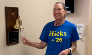 Woman in blue shirt that reads Hicks in 26 ringing a bell