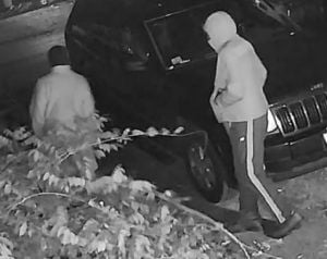 A black and white photo of two people at night with hoods.