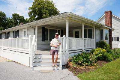 A man stands on the steps of a house.