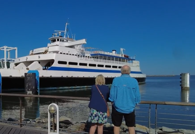 The Cape May - Lewes Ferry from the deck of the Lewes terminal while two people face the boat.