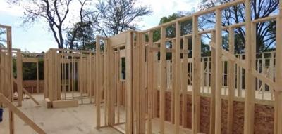 The foundation for a home under construction. Wooden poles are standing in formation.