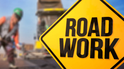 A Road Work sign with a worker in the background as an example of new projects in Wicomico County.