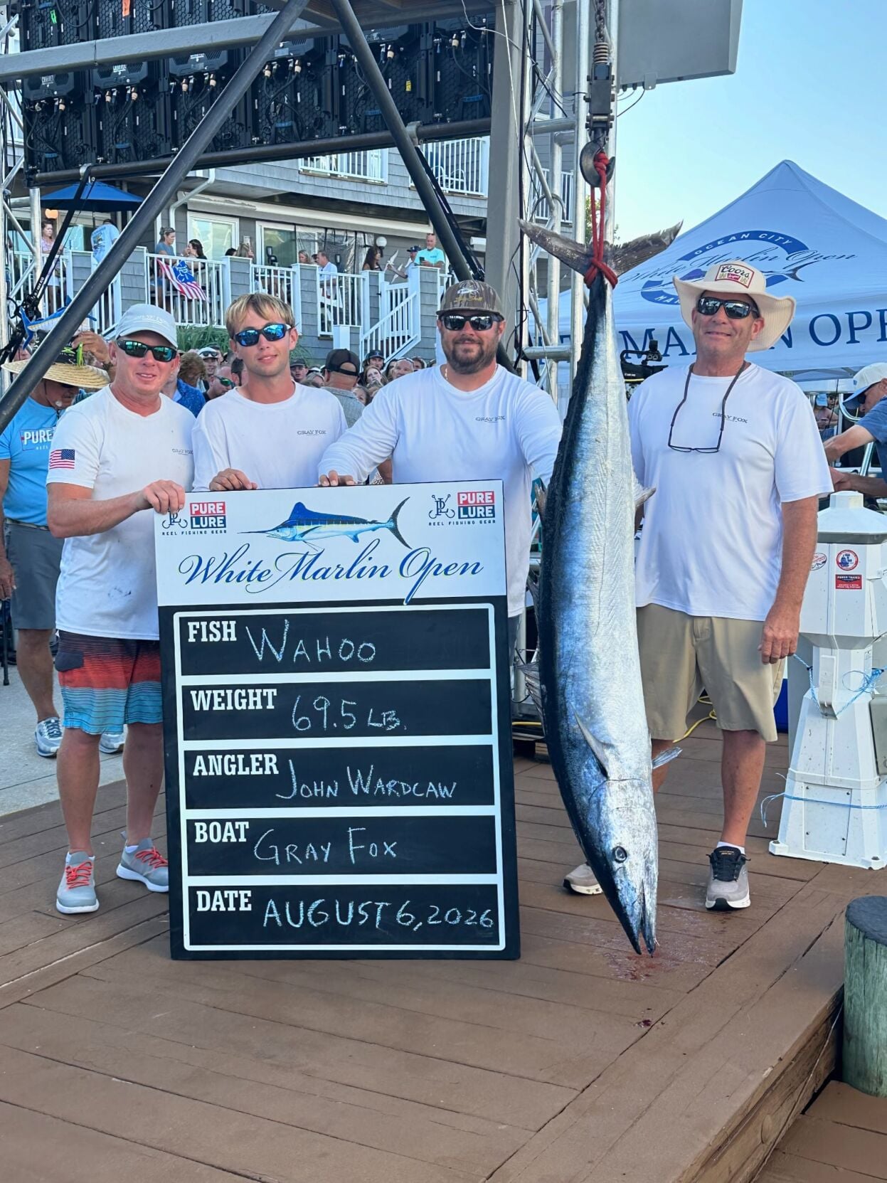 Four men posing at the scales with a 69.5 pound wahoo.