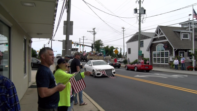 Paradegoers wave flags at the American Legion Memorial Day Parade in Lewes