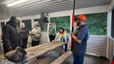 A volunteer teaching women about the mechanics of the shotgun. 
