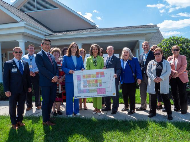 U.S. Sens. Chris Coons and Lisa Blunt Rochester and U.S. Rep. Sarah McBride standing with staff from Beebe Healthcare holding plans for its Coordinated Care Center.