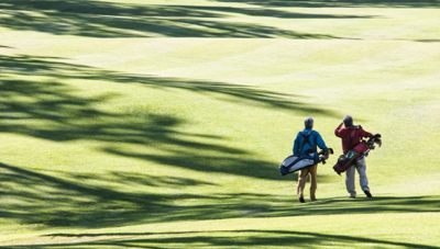 two golfers walk a course 
