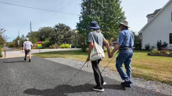 Two people holding hands walking with white canes