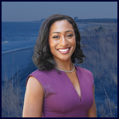 A headshot of Tia with a purple dress on and a dark blue beach background.