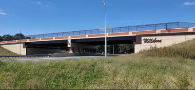 Overpass with the words Millsboro on the right support side. State of Delaware's outline is in the middle.