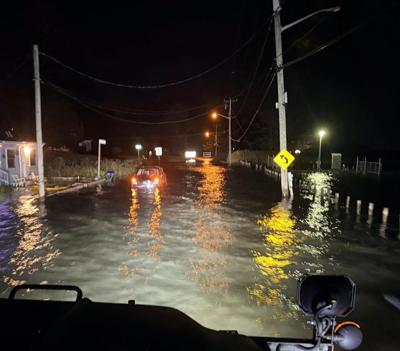A car with water over halfway up on the cars door in the night time with water flowing.