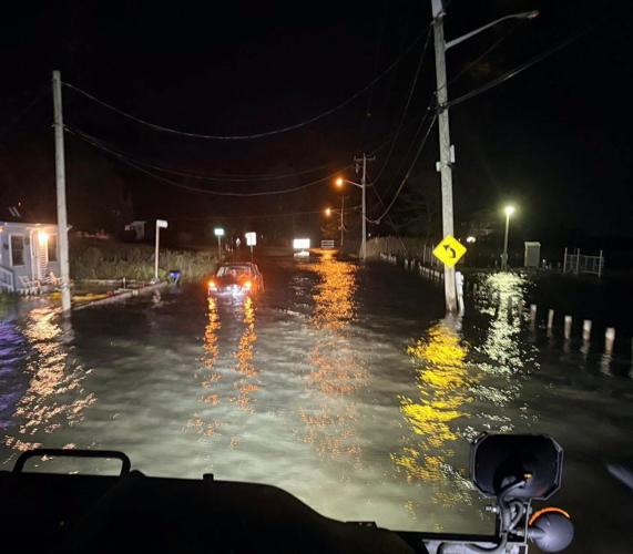 A car with water over halfway up on the cars door in the night time with water flowing.
