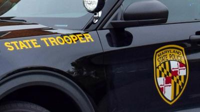 A dark colored Maryland State Police vehicle with the MSP logo on the driver side door.