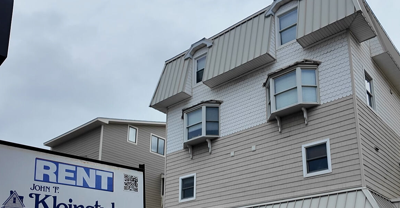A rent sign in front of a residential building.