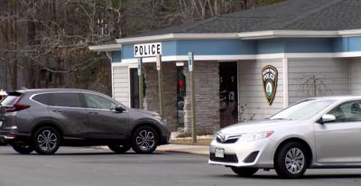 Two cars parked outside of a police station.