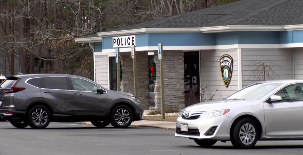 Two cars parked outside of a police station.