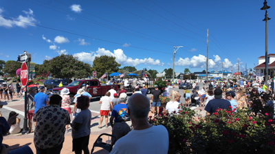 Crowds lining the sidewalks watching parade floats. 