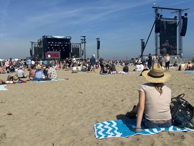 A girl watches the performance from her spot on a blanket in the sand.