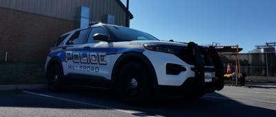 A blue and white Millsboro Police car parked outside.
